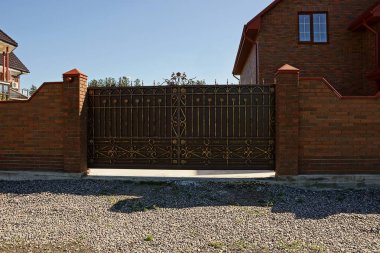 Kahverengi tuğla çit ve yol yakınında özel bir ev ile kapalı kapılar