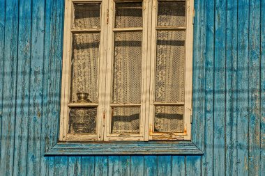 Mavi ahşap duvarüzerinde bir perde ile eski pencere