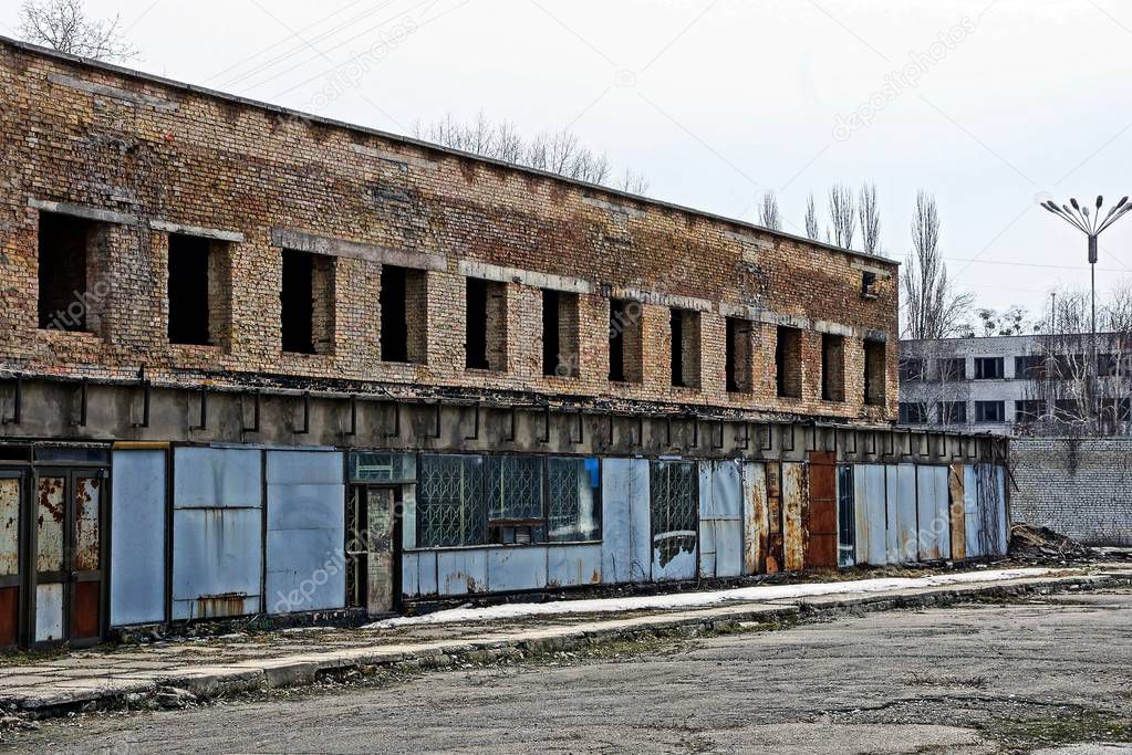ruins of a brick building with empty windows behind an iron fence