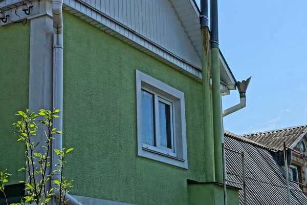 one white window on the green plastered wall of a private house