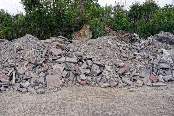 Heaps of construction debris near the road near trees and bushes