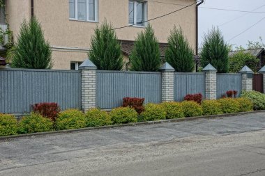 yol dışında yeşil çim ve süs bitkileri dışında metal ve tuğla uzun bir gri çit
