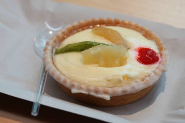 meyve parçaları ile bir yuvarlak tartlet bir kaşık ile bir kağıt tepsiüzerinde