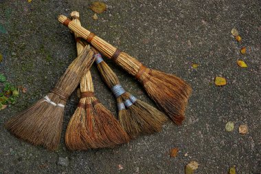 Eski süpürgeler bir dizi yaprakları ile gri bir yolda yalan
