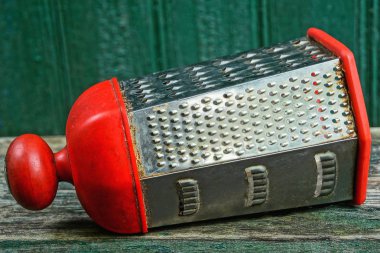 yeşil bir duvara karşı ahşap bir masa üzerinde yatan gri metal kirli rende