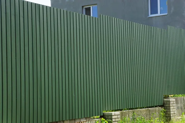 long private green metal fence outside in the grass