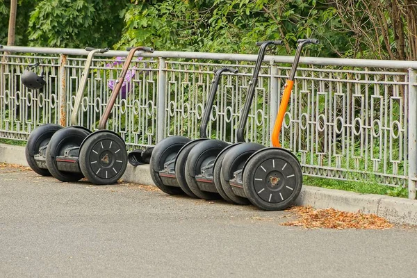 Row Electric Scooters Asphalt Road Gray Fence Park — Stock Photo, Image