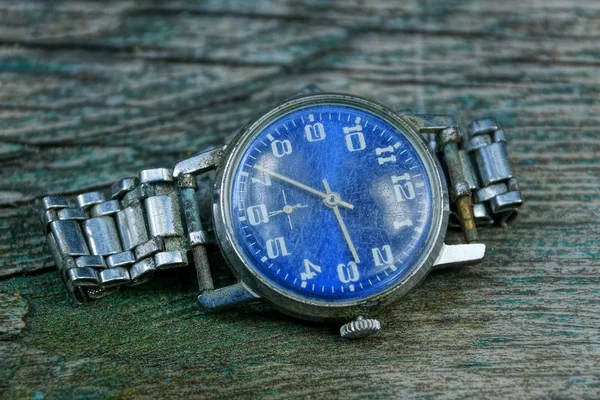 灰色のテーブルの上に金属のストラップを持つ古いみすぼらしい時計 — ストック写真