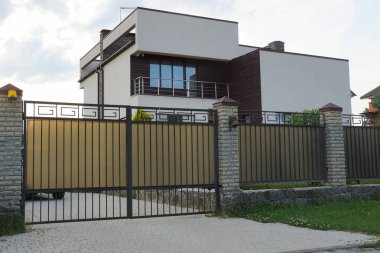 bir balkon ile özel bir evin önünde gri metal kapı ve çit