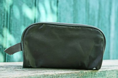 küçük bir gri çanta bir çanta ahşap bir masa üzerinde duruyor