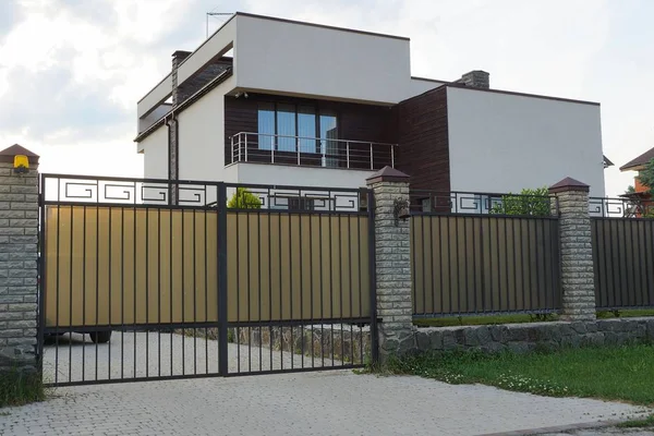 bir balkon ile özel bir evin önünde gri metal kapı ve çit