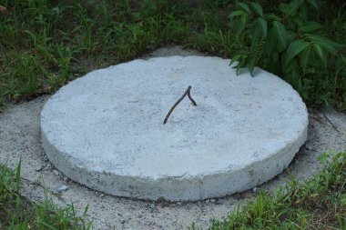 yeşil çim sokakta bir büyük gri beton rögar