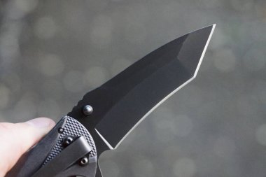 el gri arka plan üzerinde siyah bıçak ile katlanır bıçak tutar