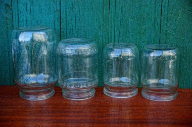 Ahşap duvara yakın bir masada eski cam kavanozlar