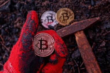 Bozuk para yere ve çekice karşı eldivenli bir elin üzerinde duruyor.