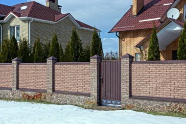 uzun kahverengi tuğla çit parçası ve karda yolda kapalı bir kapı