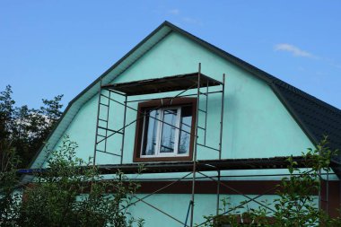 özel bir evin yeşil cephesinde bir pencere ile tavan arası onarım