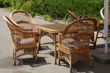 kahverengi hasır ahşap sandalye ve sokakta gri asfalt üzerinde bir masa standı