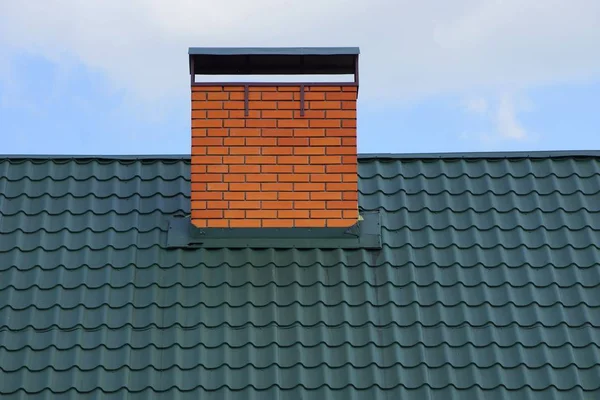 空と雲に対する緑のタイル屋根の茶色のレンガの煙突パイプ — ストック写真