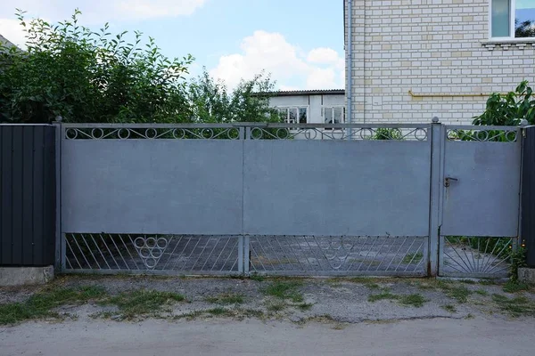 长灰色封闭的金属门和部分围栏在农村街道 — 图库照片