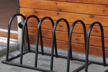 kahverengi ahşap duvarın yanındaki kaldırımda bir bisiklet park siyah metal çubuklar bir satır