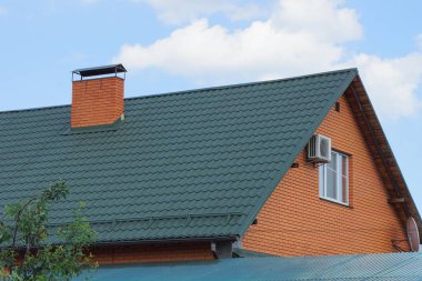 gökyüzüne karşı yeşil kiremitli çatı ve baca altında kahverengi bir evin parçası