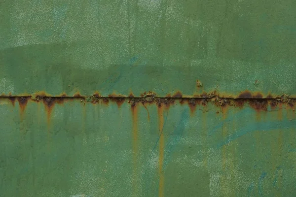 green metal texture from an old iron wall with a brown rusty seam