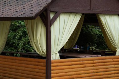 sokakta beyaz perdeler ile kahverengi ahşap çardak parçası