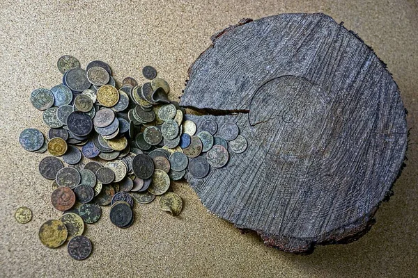 一堆旧硬币靠近一块圆形的木头 — 图库照片