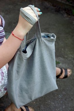 Kızın elinde gri bez torbası