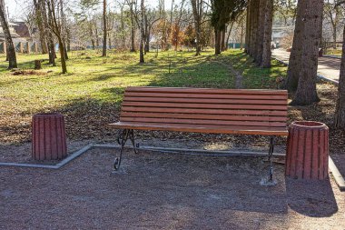 Parkta kahverengi bir bank ve bir vazo