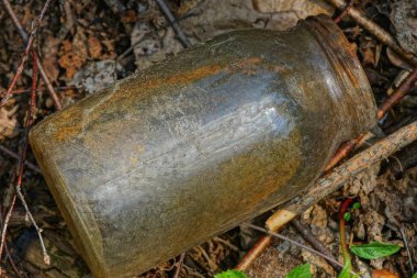 bir kirli cam kavanozdan çöp doğada yerde yatıyor