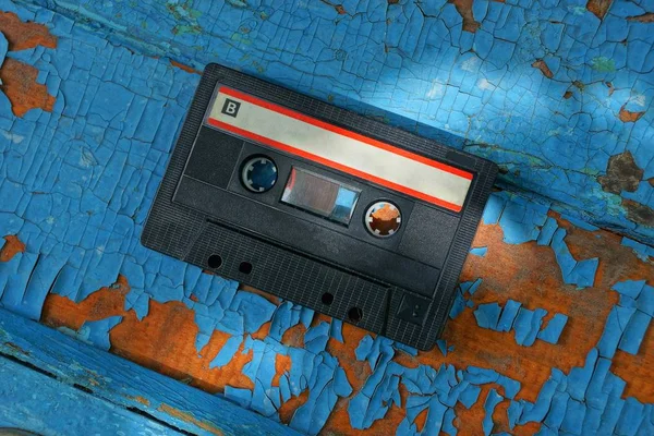 Одна Черная Старая Аудиокассета Лежит Синей Потрепанной Доске — стоковое фото