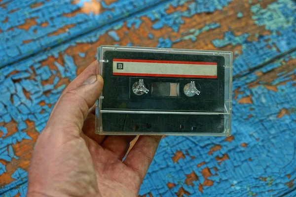 Одна Старая Аудиокассета Прозрачной Коробке Лежащей Руке Синем Фоне — стоковое фото