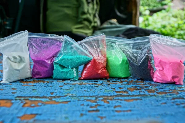 Row Plastic Bags Colored Sand Blue Table — Stock Photo, Image