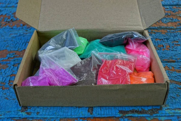 Pila Bolsas Plástico Con Arena Colores Una Caja Papel Abierta — Foto de Stock