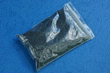 siyah kum ile küçük bir plastik torba mavi masada