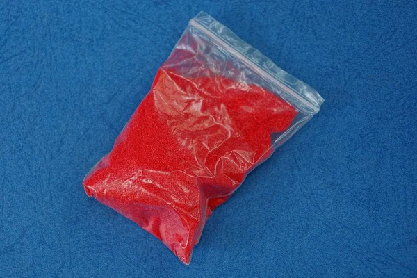 Een Kleine Plastic Zak Met Rood Zand Blauwe Tafel — Stockfoto