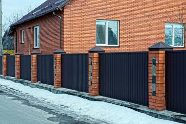 karda yol tarafından sokakta demir ve tuğlayapılmış kahverengi bir çit parçası