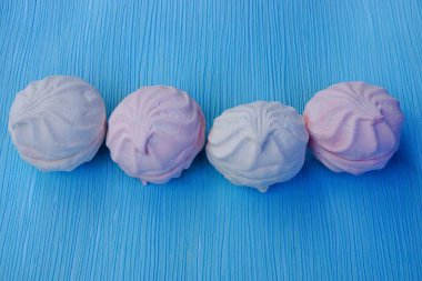 Mavi bir masada yuvarlak, pembe şekerlemeler.