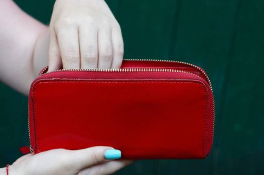 bir kızın elinde büyük açık kırmızı deri cüzdan