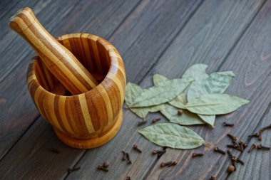 bir tahta harç yuvarlak biber ve bir masa üzerinde bir defne yaprağı