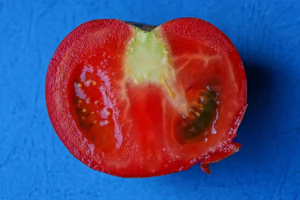 Jeden Czerwony Pomidor Plasterkowane Leży Niebieskim Stole — Zdjęcie stockowe