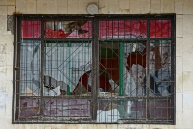 gri bir duvarda bir ızgara ile eski kırık pencere