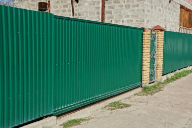 yolun yakınındaki sokakta demir yeşil çit ve kapalı kapıların bir parçası