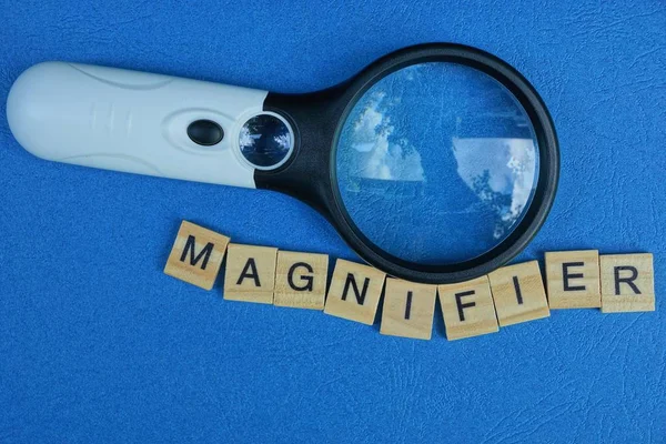 magnifier from the word of wooden letters on a blue table