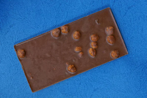 Barra Marrón Chocolate Con Nueces Encuentra Una Mesa Azul —  Fotos de Stock