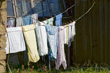 Güneşli bir günde bahçede yıkandıktan sonra giysi ve çarşaf kurur