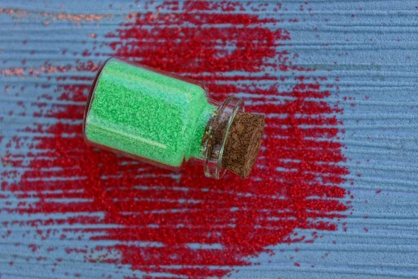 Glass Bottle Green Sand Lies Blue Table Red Sand — Stock Photo, Image
