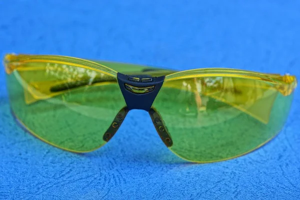 one yellow sunglasses lie on a blue table